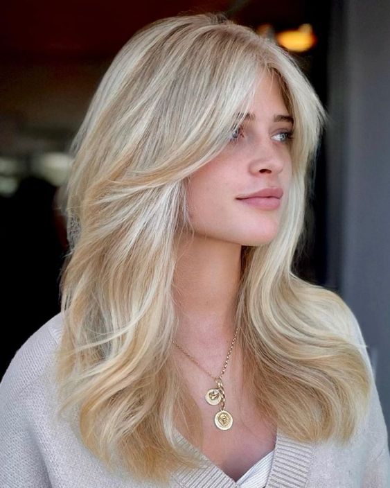 a warm sandy butterfly haircut with bleached blonde balayage on top and a bit of volume looks stylish and pretty