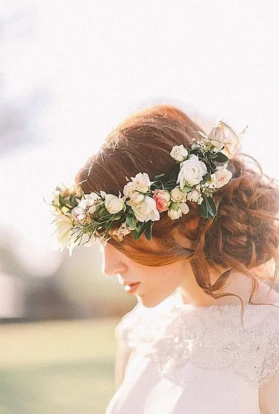 a wavy and curly side bun with some waves down and a fresh flower crown for looking boho and romantic