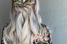 a wavy half updo with a volume on top, twisted greenery decorated element and waves down