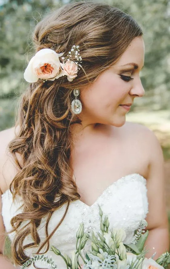 Curly side swept hair can be beautifully accentuated with fresh flowers, and this hairstyle is easy to repeat