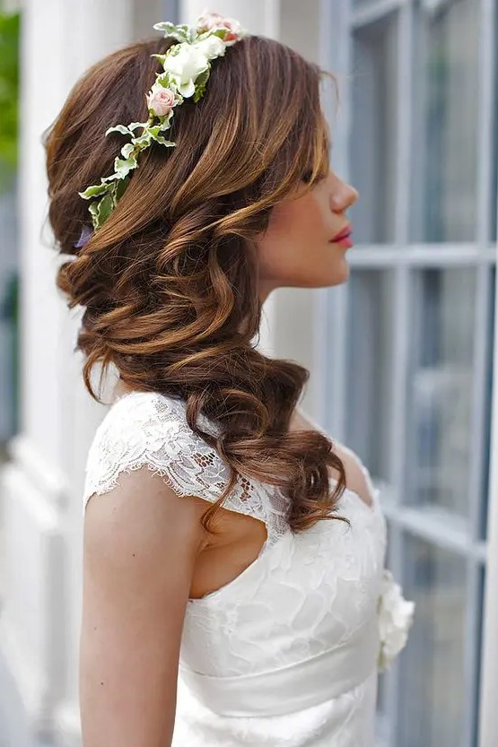 long brunette hair with a curly structure is side swept, accented with a flower crown, is a lovely solution for many brides