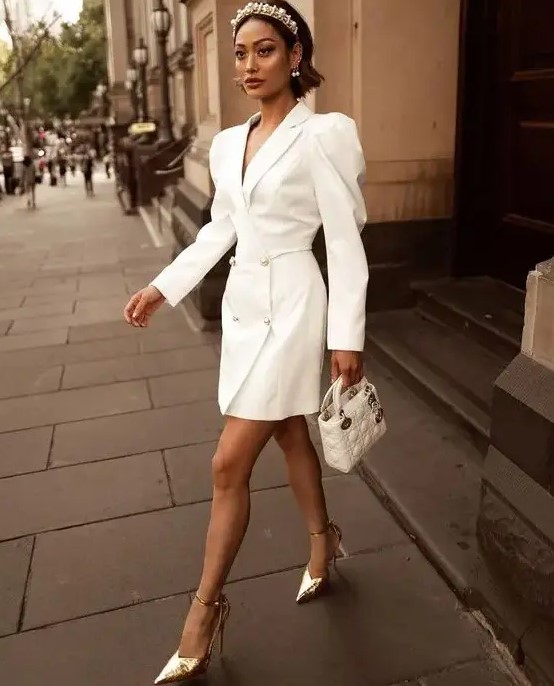 a glam and trendy tuxedo white mini dress with puff sleeves, silver buttons, a white mini bag, a pearl headpiece and silver shoes for a fashion statement