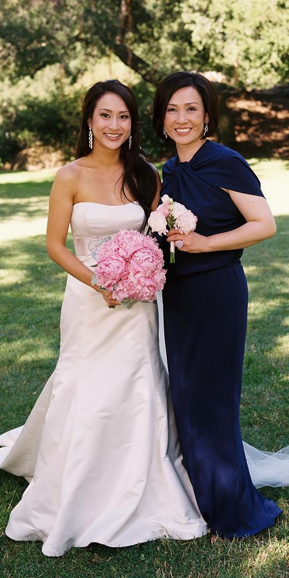 a beautiful navy maxi dress with a train and draped and tied up neckline plus chic earrings are a cool combo for the mother of the bride