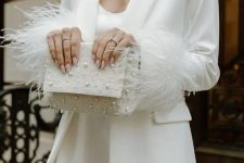 28 a white mini dress with feathers, a white blazer with feathers on the sleeves, a pearl bag and earrings