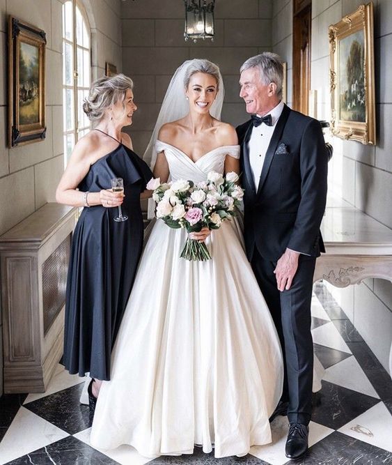 a black midi dress with a halter neckline, a ruffle detail and a pleated skirt plus spaghetti straps is a stylish idea for a mother of the bride