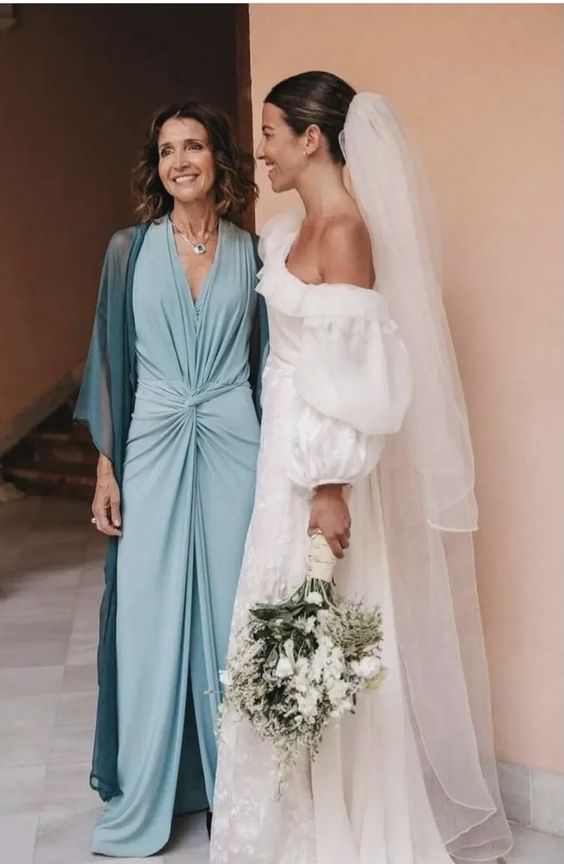 a blue draped maxi dress with a front slit and a teal cover up plus a necklace for a super chic mother of the bride look