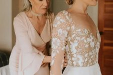 35 a blush fitting dress with a V-neckline and bell sleeves plus pearls for a very chic and feminine mother of the bride look