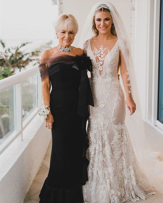 a glam and chic black strapless mother of the bride dress with a sheer detail, a large bow, a statement necklace for a wow look