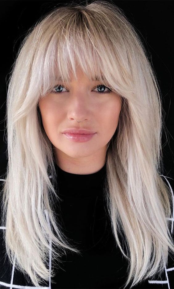 a beautiful and chic platinum blonde long hairstyle with wispy bangs and side ones, with a lot of volume is amazing