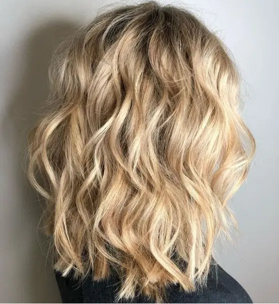 A beautiful blonde medium length wavy haircut with messy beach waves is a perfect idea for summer