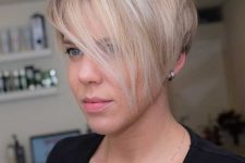 a beautiful blonde pixie haircut with icy highlights and long side bangs that can be worn either side