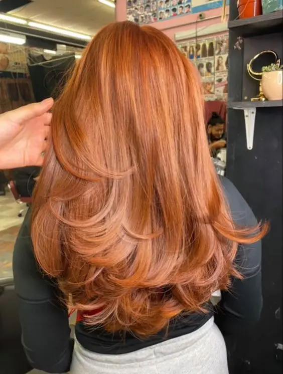 a beautiful copper long butterfly haircut with some highlights and curled ends, a lot of volume is amazing