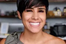 a black pixie haircut with long side swept bangs looks full at the crown and very airy and lovely