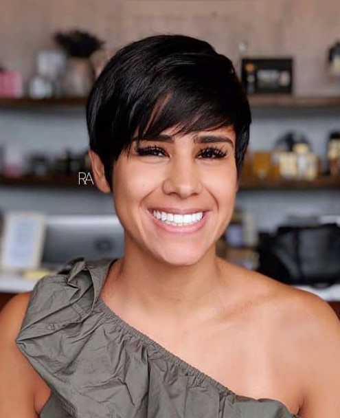 a black pixie haircut with long side swept bangs looks full at the crown and very airy and lovely