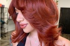 a bold red medium butterfly haircut with curled ends and a lot of volume looks very eye-catchy and very bright