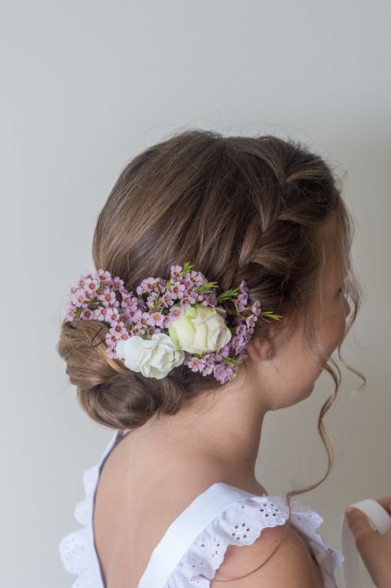 a braided halo with a bump on top and a low bun, fresh flowers tucked in is a chic and lovely idea for a flower girl