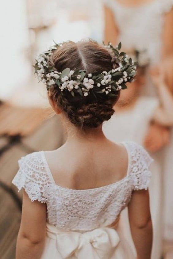 a braided low bun with a fresh flower crown are a beautiful and classy combo for a flower girl look