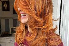a copper voluminous butterfly haircut on long hair, with blonde highlights and curled ends is adorable