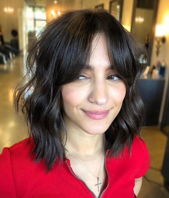 a dark brown shaggy long bob with messy waves and bottleneck bangs is a very chic and cool idea