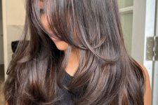 a dark brunette butterfly haircut with a shiny finish and wavy ends is a catchy and stylish idea to try