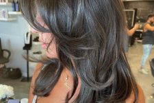 a dark brunette butterfly haircut with curled ends and a bit of volume is a chic and eye-catching idea