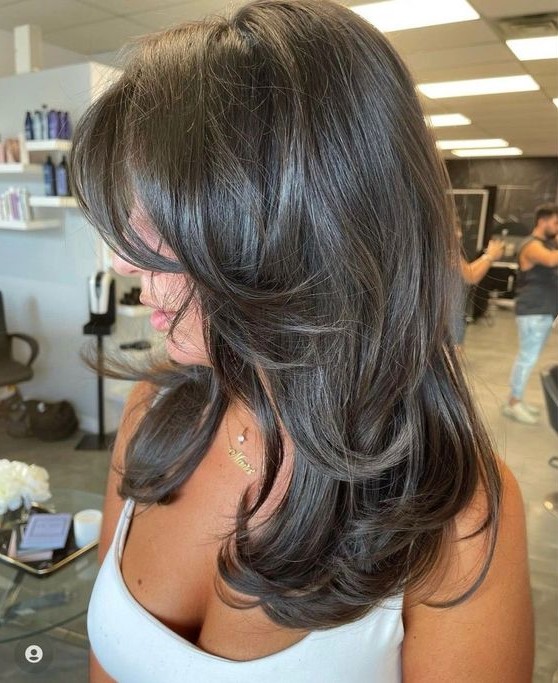 A dark brunette butterfly haircut with curled ends and a bit of volume is a chic and eye catching idea