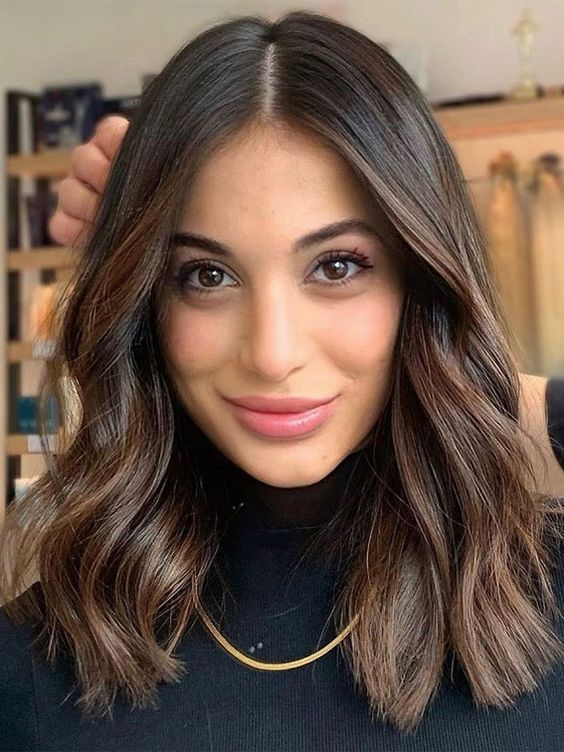a dark brunette layered haircut with waves and a bit of highlights is a cool and chic idea of a hairstyle