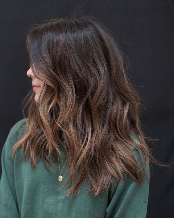 A dark brunette medium length haircut with an ombre effect, waves and volume is a very eye catching idea