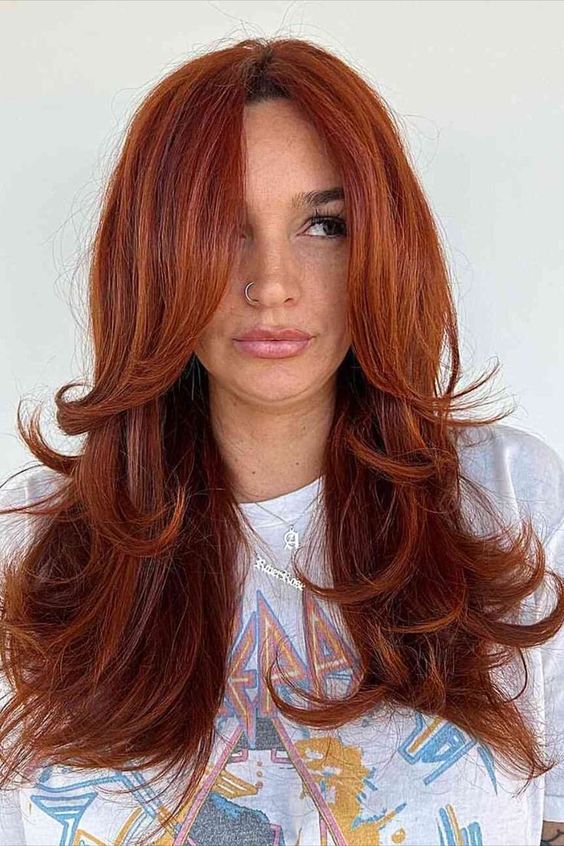 A fab red butterfly haircut on long hair, with a lot of volume, face framing layers and curled ends is jaw dropping