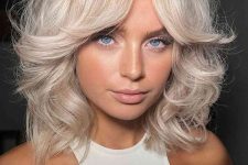 a gorgeous platinum blonde shoulder-length haircut with a lot of volume and curls is amazing for rocking now