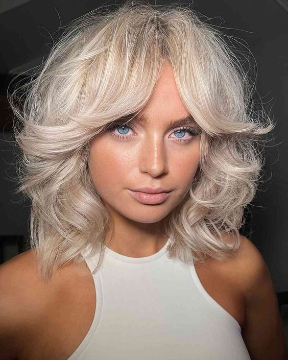 a gorgeous platinum blonde shoulder-length haircut with a lot of volume and curls is amazing for rocking now