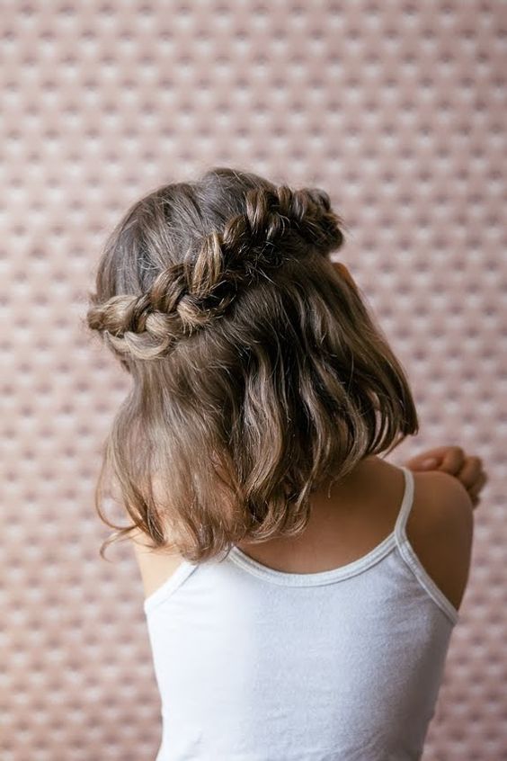 a large loose braid as a halo, with wavy hair down is a cool idea for a boho flower girl look