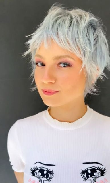 a long and messy pale blue pixie cut with a touch of mullet, with bangs and a lot of volume and texture