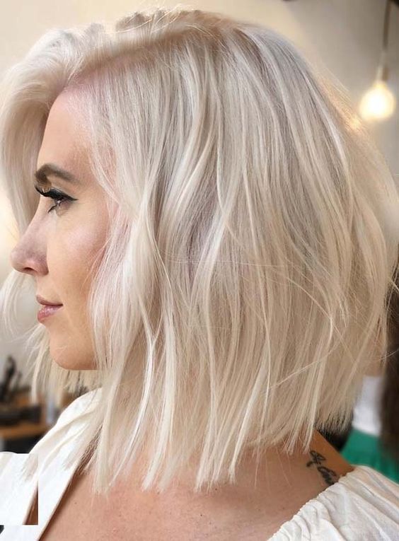 a long layered platinum blonde bob with side part and a lot of volume plus a bit of waves is a stylish idea for a modern look