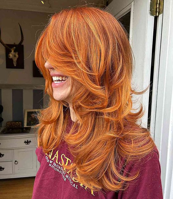 a lovely ginger butterfly haircut with blonde highlights and curtain bangs is a chic and catchy idea to go for