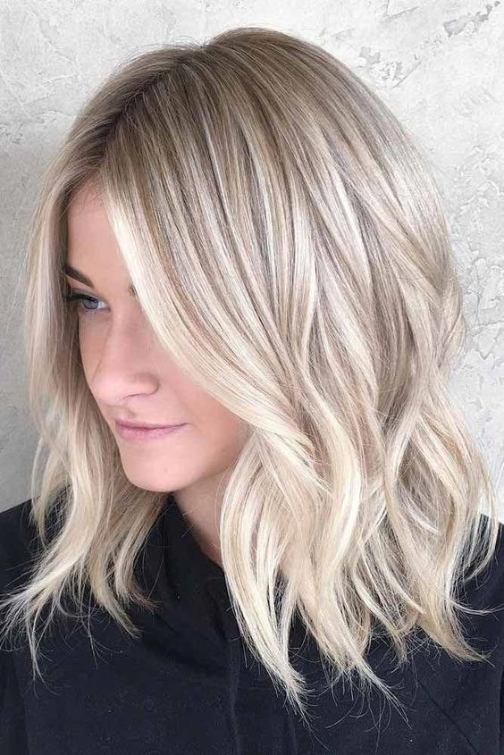 A lovely icy blonde shoulder length haircut with waves and a bit of volume is a stylish and chic solution