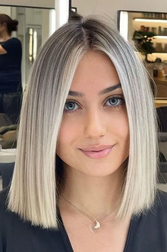 a lovely outgrown platinum blonde bob with a darker root and straight hair is a cool idea to rock, looks very chic