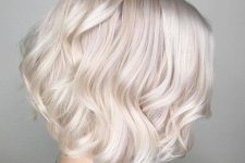 a lovely platinum blonde asymmetrical midi bob with waves and a bit of volume looks very chic and neat
