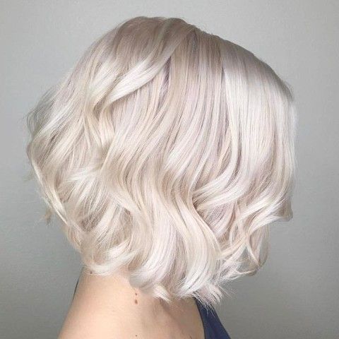 a lovely platinum blonde asymmetrical midi bob with waves and a bit of volume looks very chic and neat