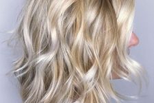 a medium-length blonde shaggy haircut with a darker root, waves and volume is a very eye-catching idea