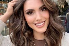 a medium-length chocolate brown hairstyle with cold brew highlights, waves and volume is a lovely idea to try