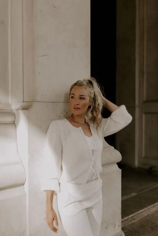 a modern casual bride-to-be wearing white trousers and a top plus a light and semi-sheer cardigan on top