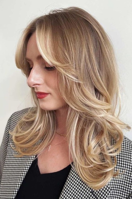 a pretty golden blonde medium butterfly haircut with side bangs and curled ends is a lovely and chic idea