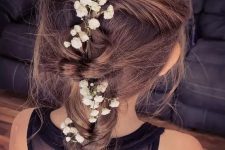 a pretty messy boho braid with a messy volume on top and some baby’s breath tucked into the braid