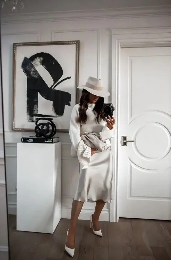 a slip midi dress, a white sweater over it, white shoes, a hat and a large clutch for a winter bridal shower