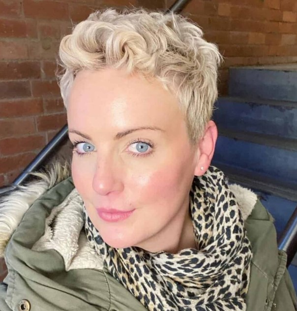 a super short blonde wavy pixie haircut with some extra length on the sides and back and it looks chic