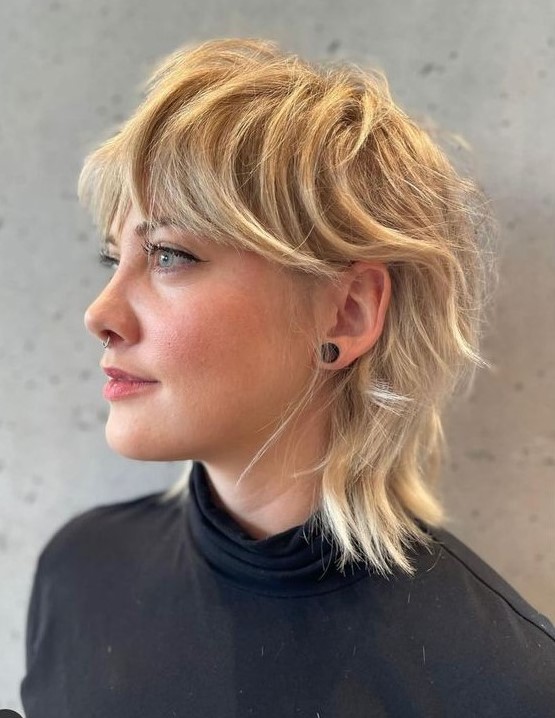 a textural mullet in blonde shades, with bangs, longer hair on top and shorter hair on the sides and back
