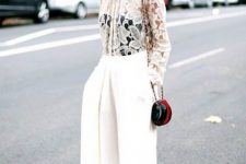 a white lace top, a black corset underneath, white wideleg pants, a small red bag for a chic winter bridal shower look