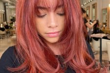 an extra bold red butterfly haircut with face-framing layers and wispy bangs, volume and curled ends is amazing