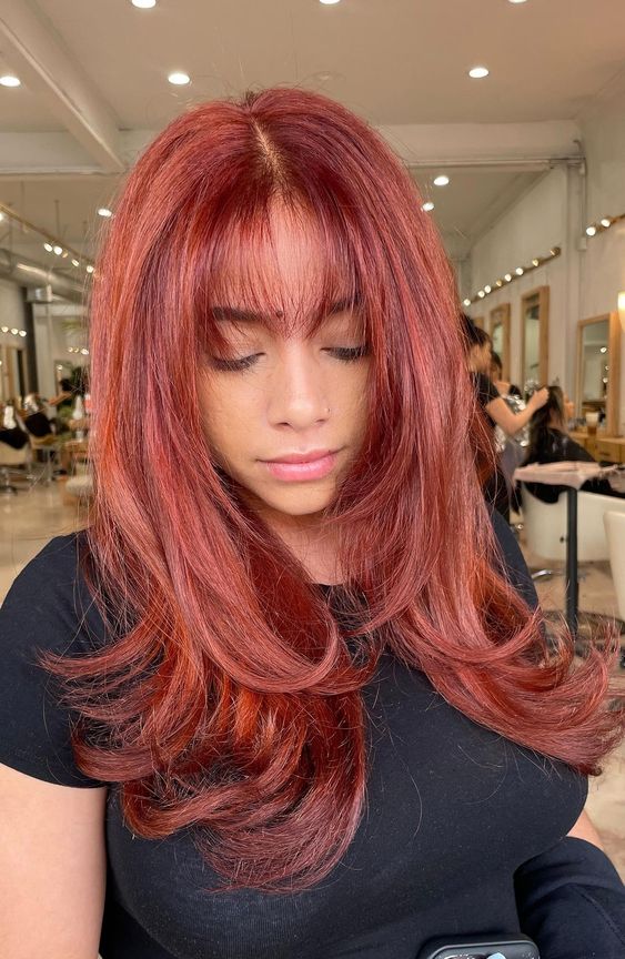 An extra bold red butterfly haircut with face framing layers and wispy bangs, volume and curled ends is amazing
